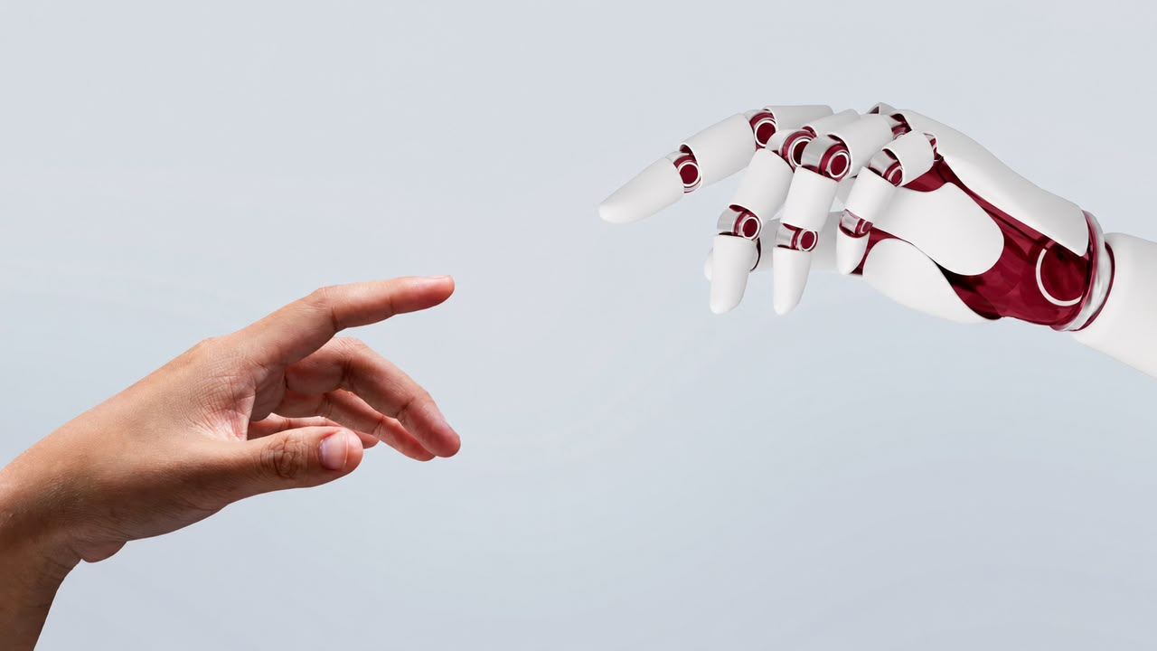 Une main humaine et une main robotique se rejoignent — collaboration humain / IA.